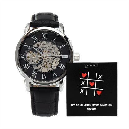 Timeless Elegance Skeleton Watch mit schwarzem Echtleder-Armband und offenem Skelett-Design, präsentiert als stilvolles Geschenk für Männer – ein Liebesbeweis von ihr an ihn.